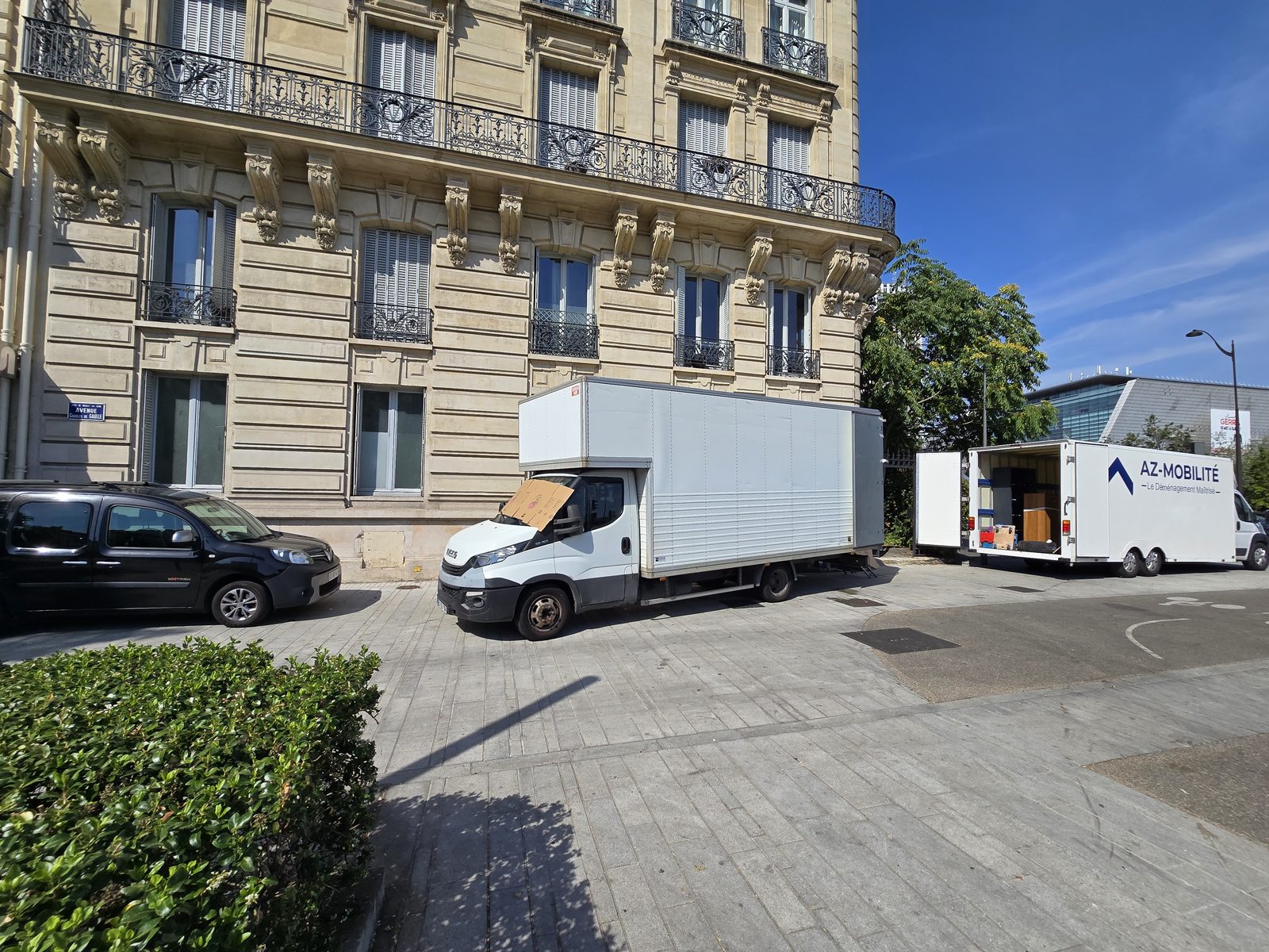 Deux camions AZ Mobilité stationnés devant une grande demeure