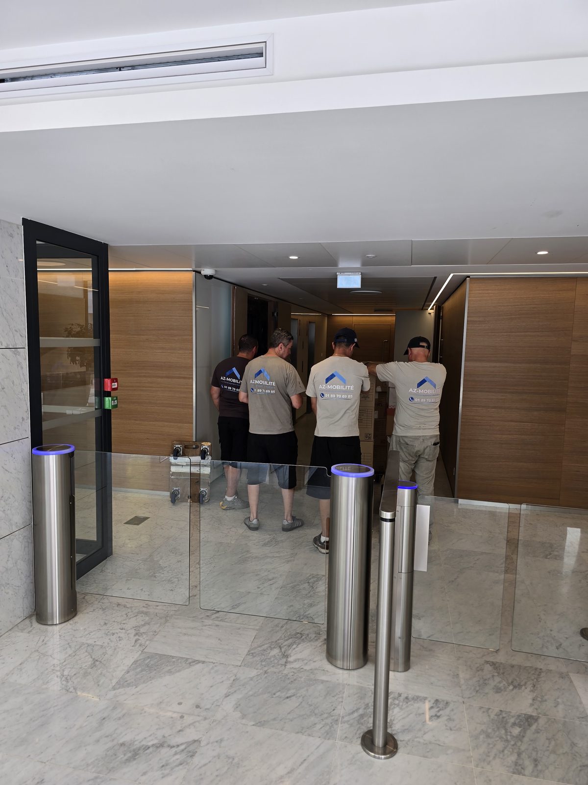 Équipe AZ Mobilité franchissant les portiques du hall d'un immeuble de bureaux