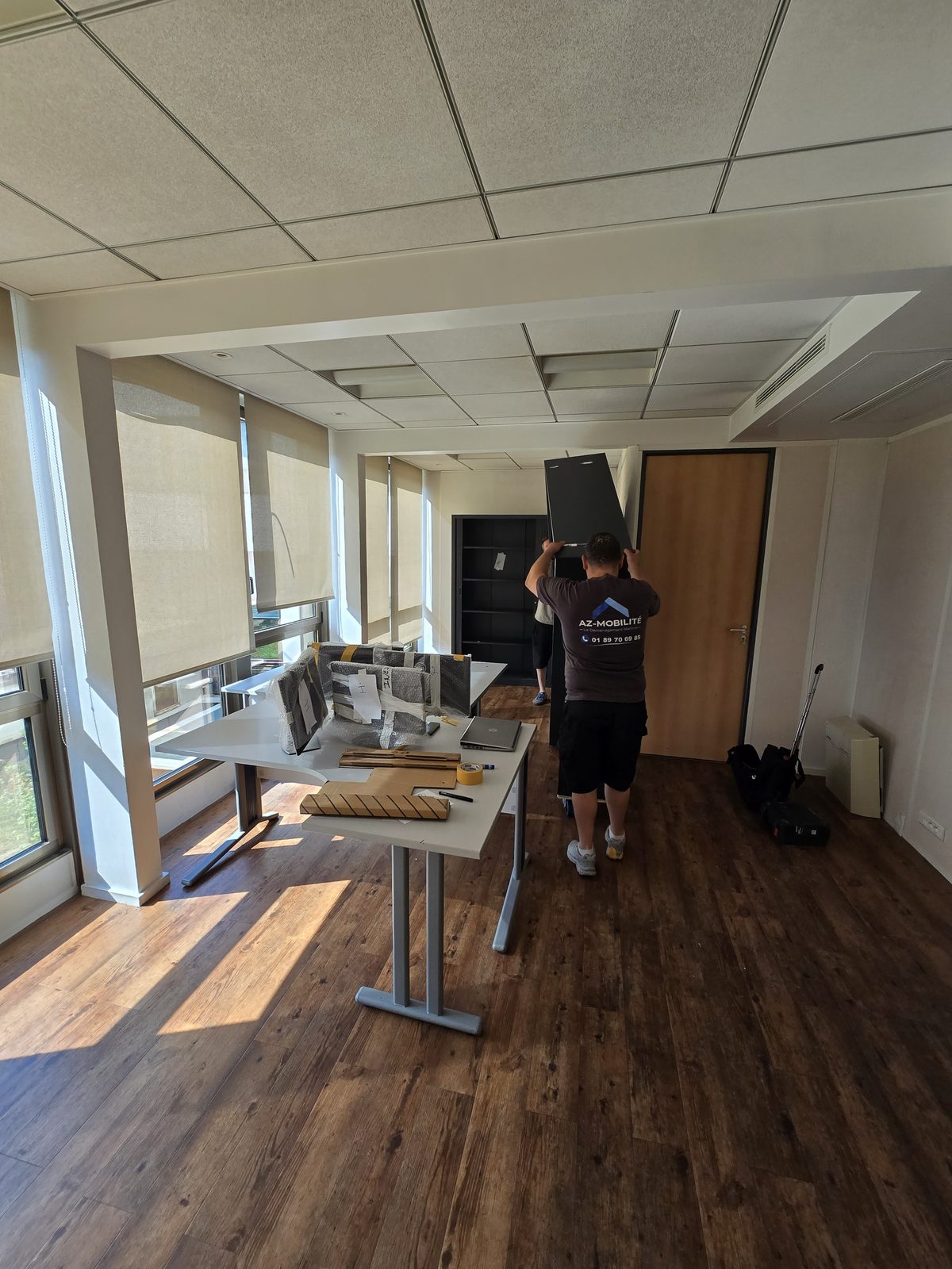 Déménageur AZ Mobilité manutentionnant une armoire de bureau dans un open space