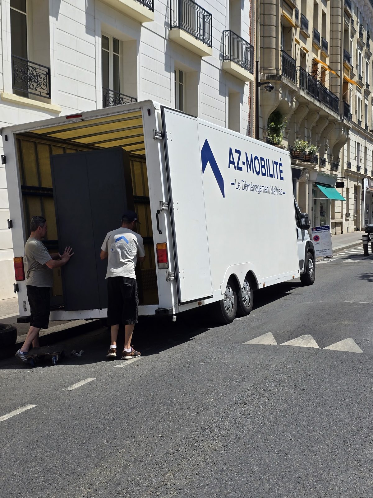Camion AZ Mobilité stationné sur un emplacement réservé avec panneau de signalisation déménagement, chargement d'une armoire de bureau